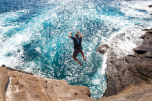 Anthony Walsh jumps off a cliff into the Pacific Ocean in Oahu, HI. Photo taken by Bhushan Thakkar