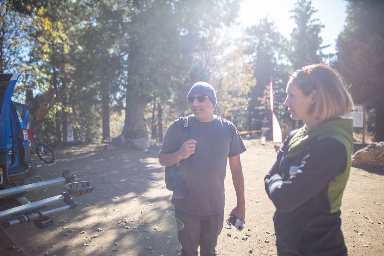 Man talking to woman in outdoor environment with trees and forest in the background