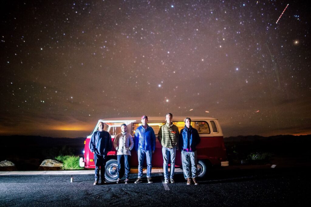 Crew infront of VW bus at night with stars overhead