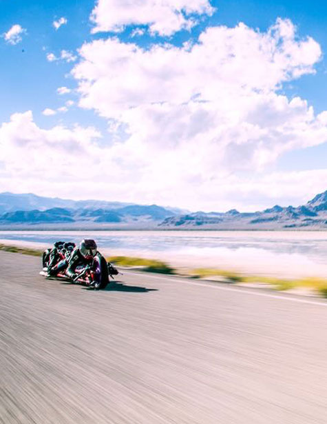 Drag racing bike driving on road with mountains in the background