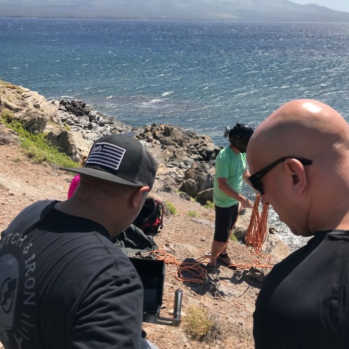 men shooting with talent on cliffside with ocean below